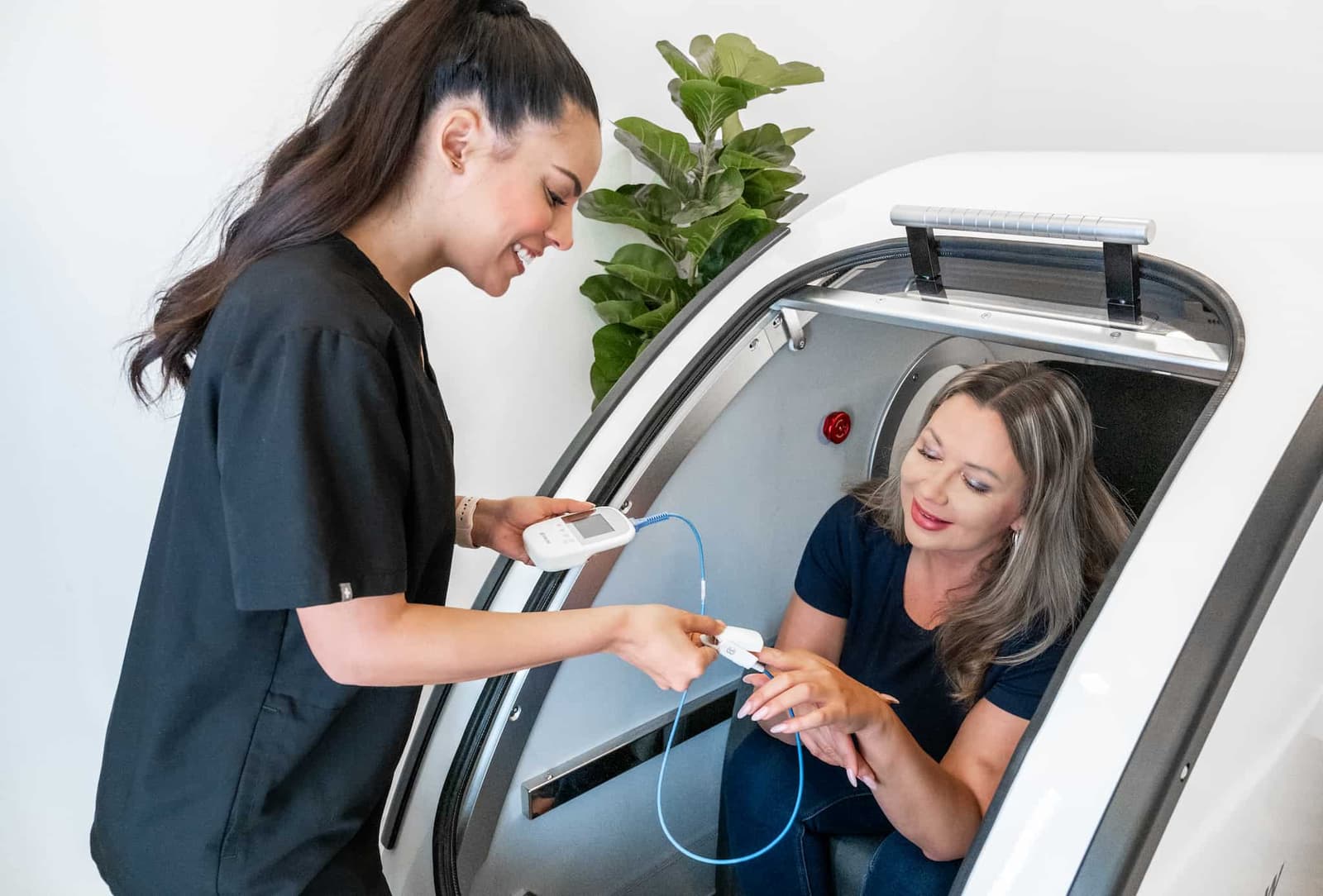 An OxyRenew technician taking a client's blood oxygen saturation and heart rate before a hyperbaric oxygen therapy session.